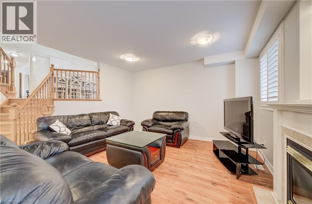 Wood-finish flooring, staircase with natural wood banister, built-in fireplace, plantation shutters, and recessed ceiling lighting - 245 Fern Crescent, Waterloo, ON