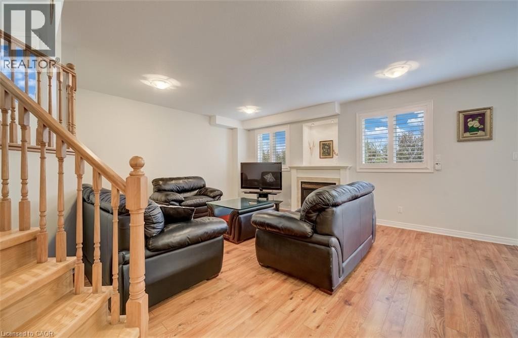 Wood-finish flooring, staircase with natural wood balusters, recessed lighting, and a fireplace with a mantel - 245 Fern Crescent, Waterloo, ON