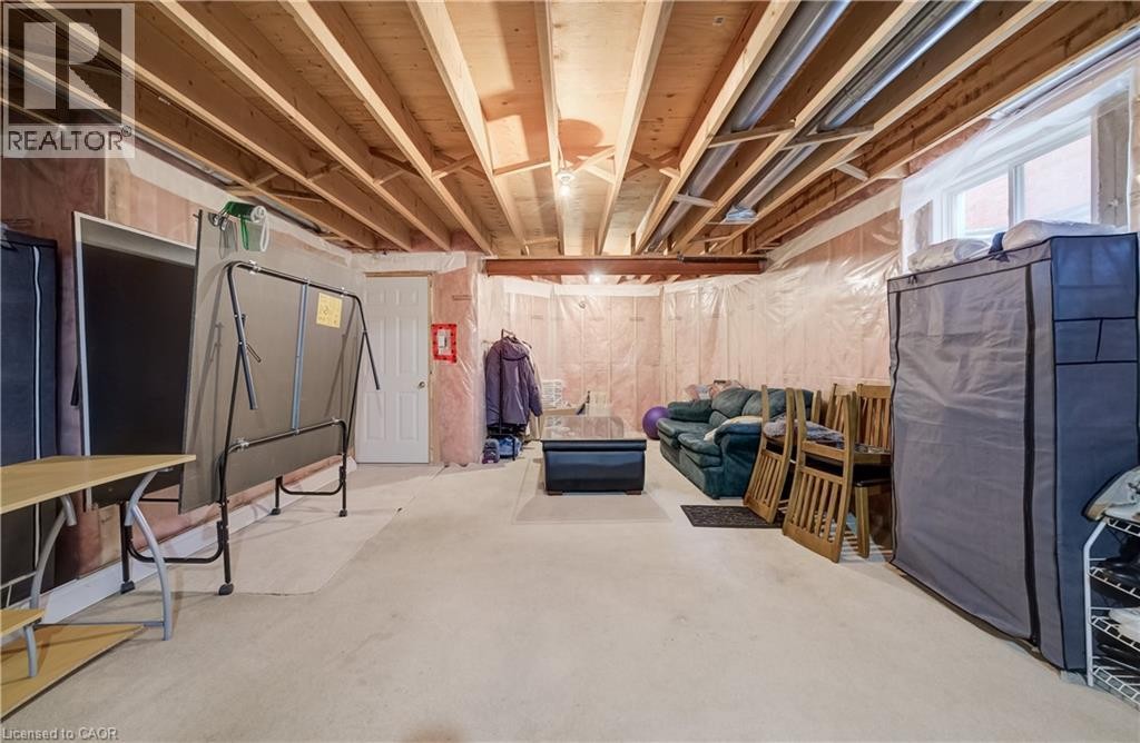 Unfinished basement with exposed ceiling joists, concrete floor, and an egress window - 245 Fern Crescent, Waterloo, ON