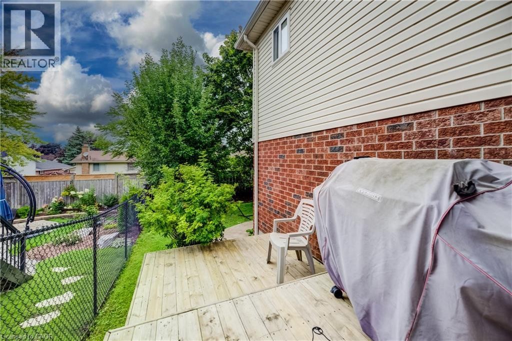 Wood deck, brick and siding exterior, chain link fence, mature landscaping, and a manicured lawn - 245 Fern Crescent, Waterloo, ON