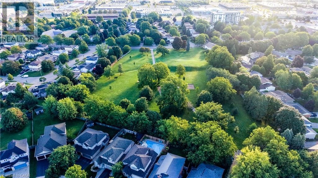 Aerial depiction of a residential area featuring detached homes, tree-lined streets, and a central green space - 245 Fern Crescent, Waterloo, ON