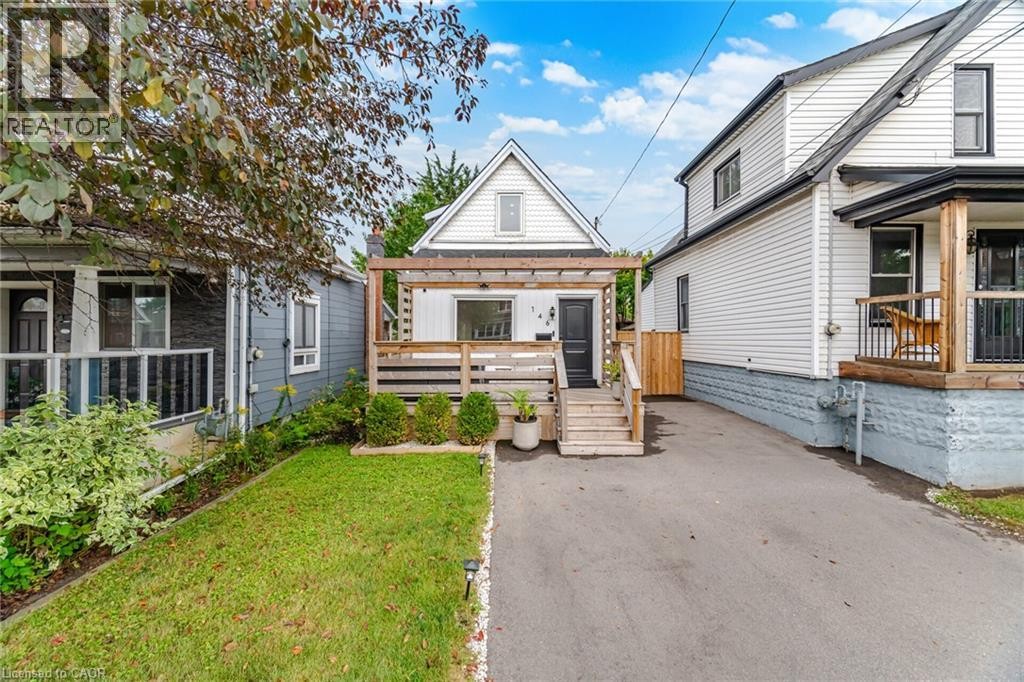 White siding exterior with a prominent front deck featuring a wooden pergola and railings - 146 Campbell Avenue, Hamilton, ON