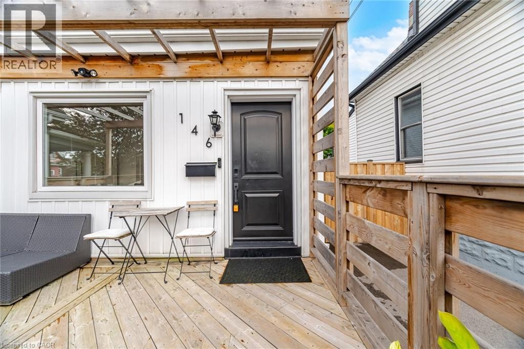 Wood-finish deck with a pergola, black front door, and white siding - 146 Campbell Avenue, Hamilton, ON