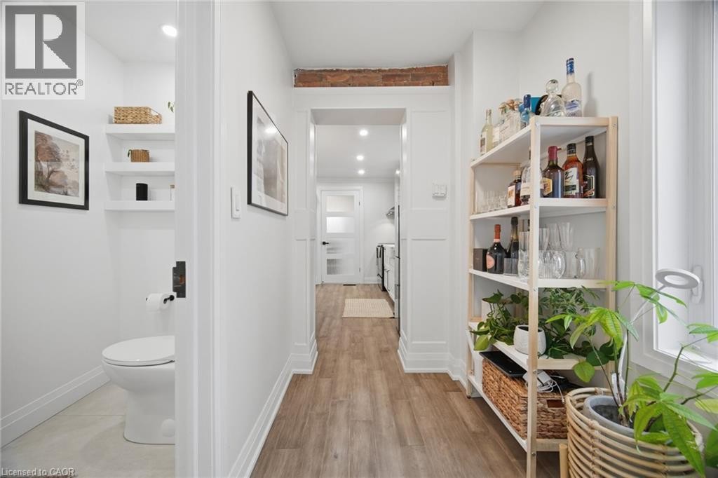 Hallway with wood-finish flooring, white paneling, exposed brick accents, and recessed lighting - 146 Campbell Avenue, Hamilton, ON