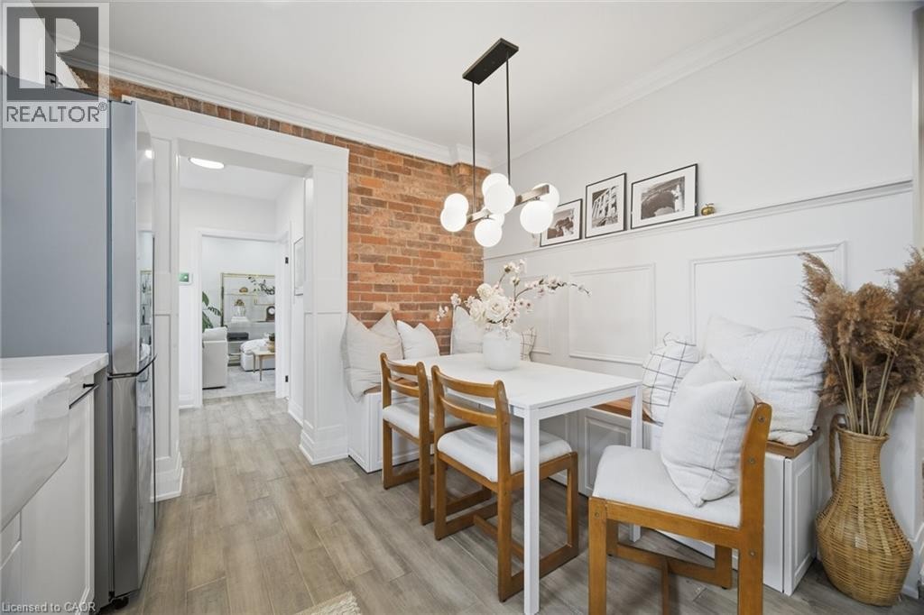 Exposed brick wall accent, built-in bench seating, wood-finish flooring, contemporary linear chandelier, detailed wainscoting - 146 Campbell Avenue, Hamilton, ON