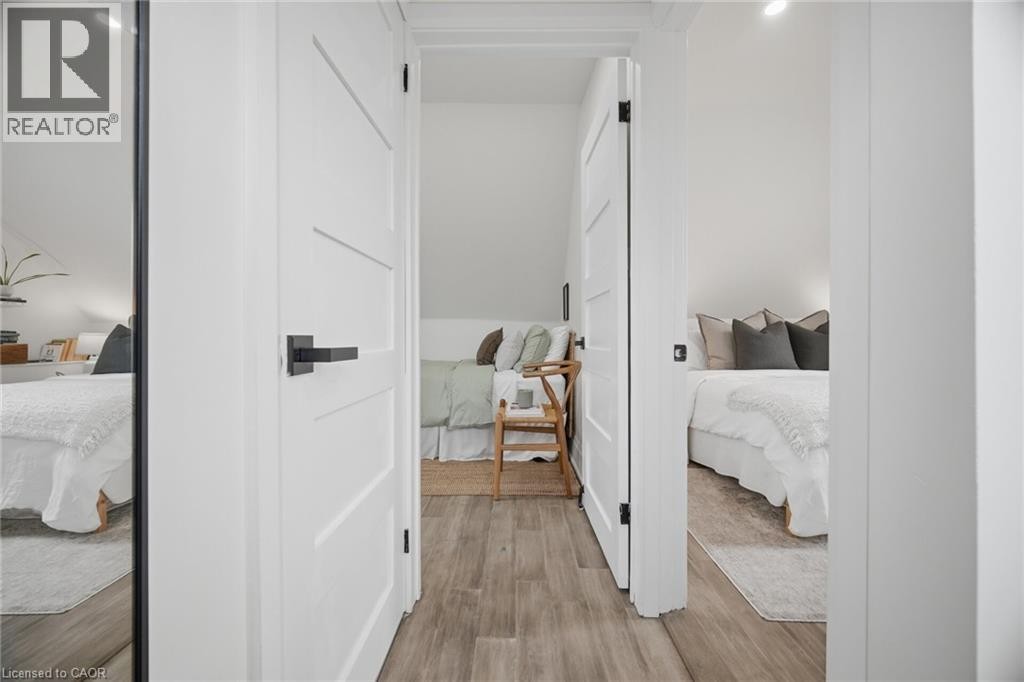 Wood-finish flooring throughout, bright white walls, and modern panel doors with matte black hardware - 146 Campbell Avenue, Hamilton, ON