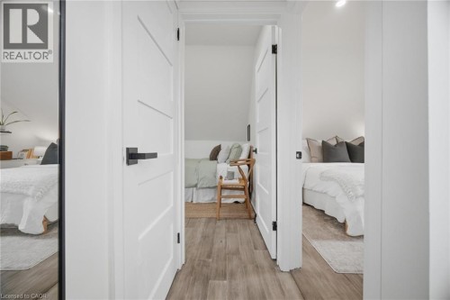 Wood-finish flooring throughout, bright white walls, and modern panel doors with matte black hardware - 146 Campbell Avenue, Hamilton, ON 