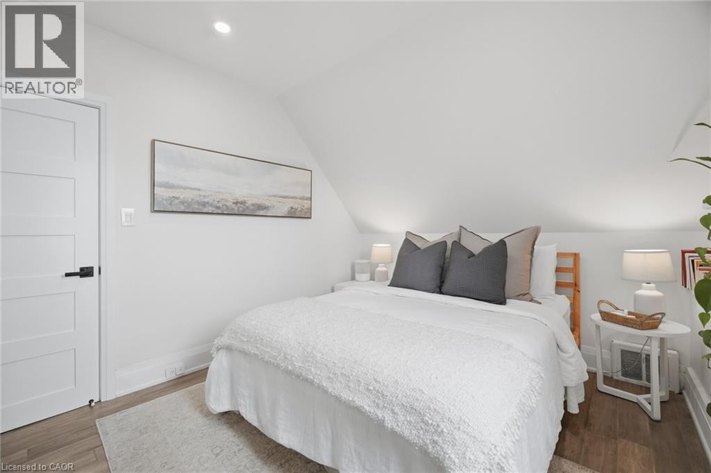 Wood-finish flooring, recessed ceiling lighting, and a paneled interior door with matte black hardware - 146 Campbell Avenue, Hamilton, ON