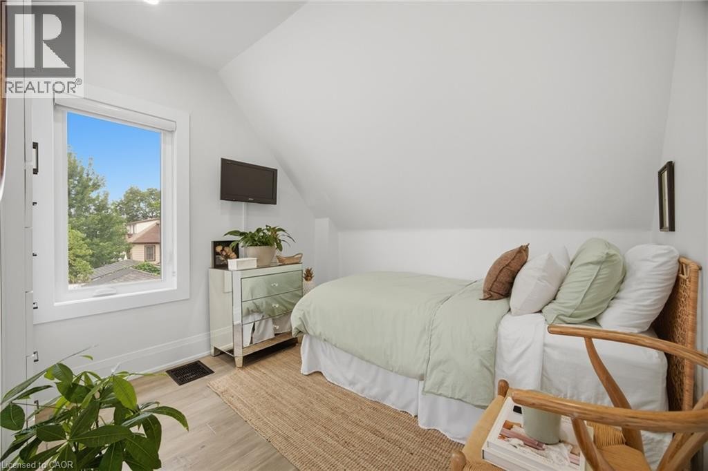 Sloped ceiling with recessed lighting, wood-finish flooring, white window trim, and a built-in recessed mirror - 146 Campbell Avenue, Hamilton, ON