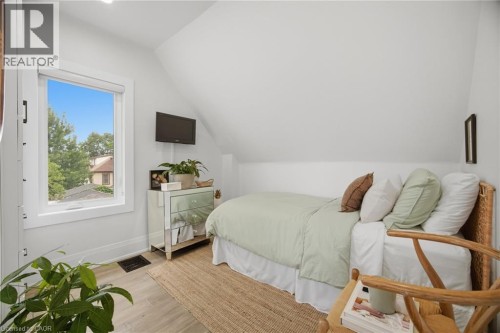 Sloped ceiling with recessed lighting, wood-finish flooring, white window trim, and a built-in recessed mirror - 146 Campbell Avenue, Hamilton, ON 