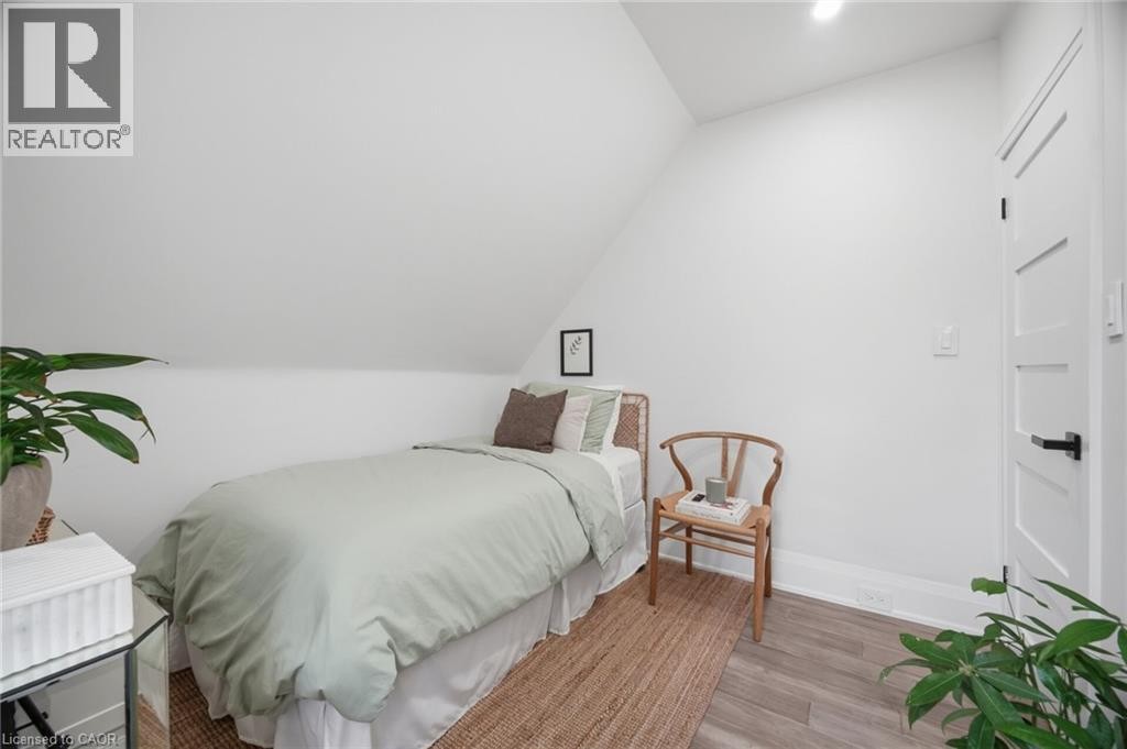 Sloped ceilings, wood-finish flooring, and a white paneled door with black hardware - 146 Campbell Avenue, Hamilton, ON
