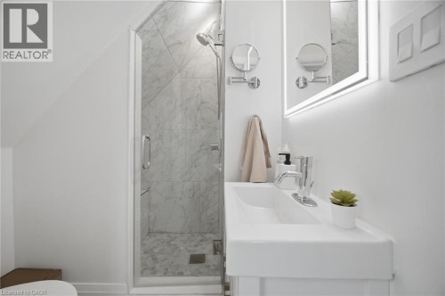 Glass-enclosed shower with marble-style tile and pebble-style flooring - 146 Campbell Avenue, Hamilton, ON 