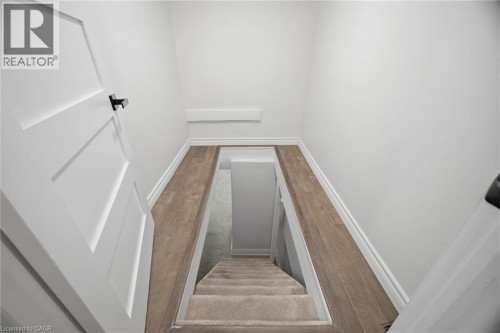 White panel doors with black hardware, wood-finish flooring, white walls, and carpeted stairs - 146 Campbell Avenue, Hamilton, ON 