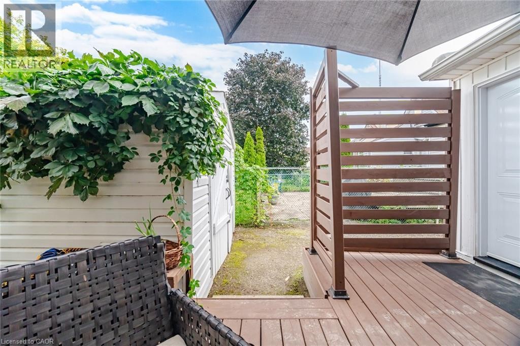 Composite wood deck with privacy screen, white exterior door, and adjacent storage shed - 146 Campbell Avenue, Hamilton, ON