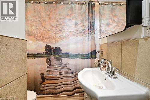 Pedestal sink featuring a chrome faucet, complemented by a decorative shower curtain - 127 Taylor Avenue, Hamilton, ON 