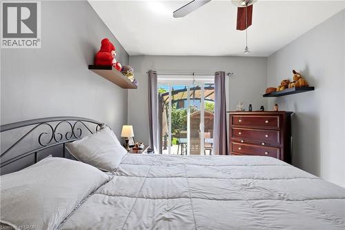 Bedroom featuring sliding glass doors to the exterior, a ceiling fan with integrated lighting, and floating wall shelves - 127 Taylor Avenue, Hamilton, ON 