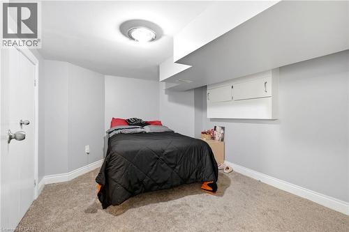 Carpeted room featuring light gray walls, white baseboards, and a flush-mount ceiling light fixture - 127 Taylor Avenue, Hamilton, ON 
