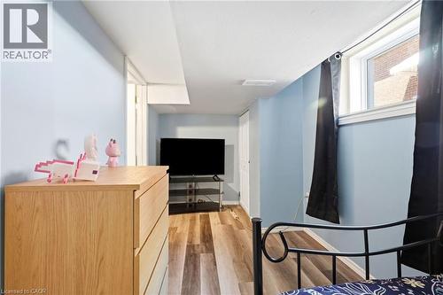 Room featuring wood-finish flooring, light blue walls, and a recessed window - 127 Taylor Avenue, Hamilton, ON 