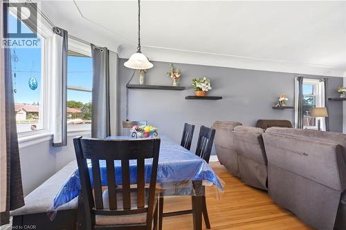 Dining area featuring wood-finish flooring, a pendant light fixture, and large windows - 127 Taylor Avenue, Hamilton, ON 