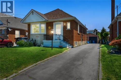 Brick bungalow with a prominent front yard, an extended driveway, and a detached garage structure - 127 Taylor Avenue, Hamilton, ON 