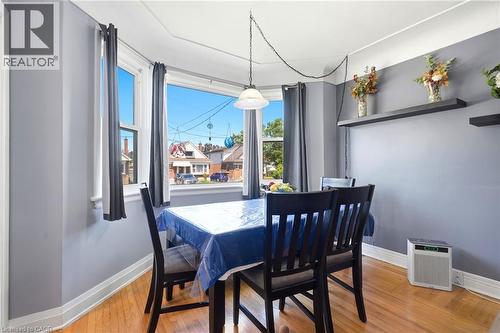 Bay window dining area featuring wood-finish flooring, a contemporary pendant light fixture, and two built-in wall shelves - 127 Taylor Avenue, Hamilton, ON 