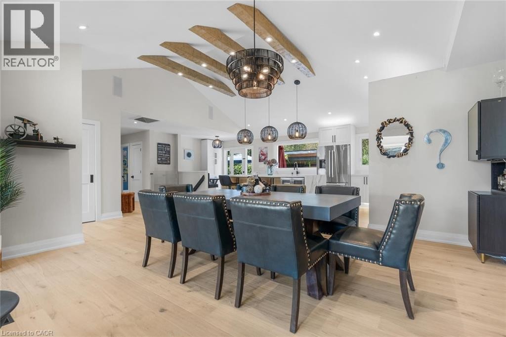 Vaulted ceiling with exposed wood beams, wood-finish flooring, recessed lighting, and a kitchen with white cabinetry and stainless steel appliances - 293 North Shore Boulevard E, Burlington, ON
