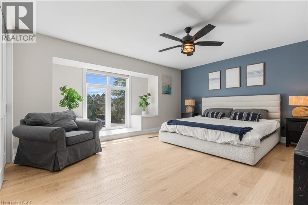 Wood-finish flooring, accent wall, window seat, ceiling fan, and large windows - 293 North Shore Boulevard E, Burlington, ON