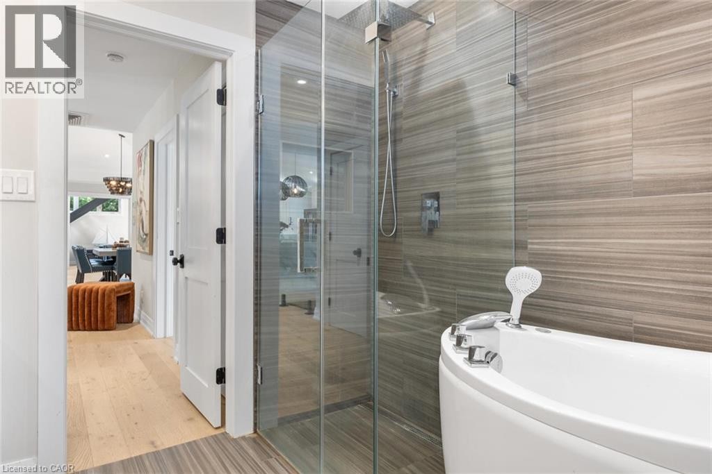 Glass-enclosed shower with a rainfall showerhead, alongside a freestanding soaking tub - 293 North Shore Boulevard E, Burlington, ON