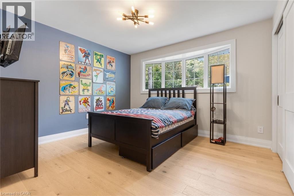 Light wood-finish flooring, a contemporary ceiling light fixture, a bay window with white trim, and a white sliding closet door - 293 North Shore Boulevard E, Burlington, ON