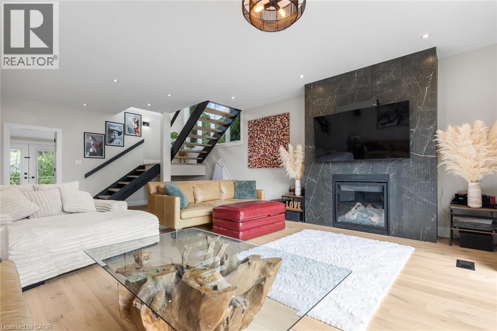 Hardwood-style flooring, recessed lighting, and a modern fireplace with a dark stone surround - 293 North Shore Boulevard E, Burlington, ON
