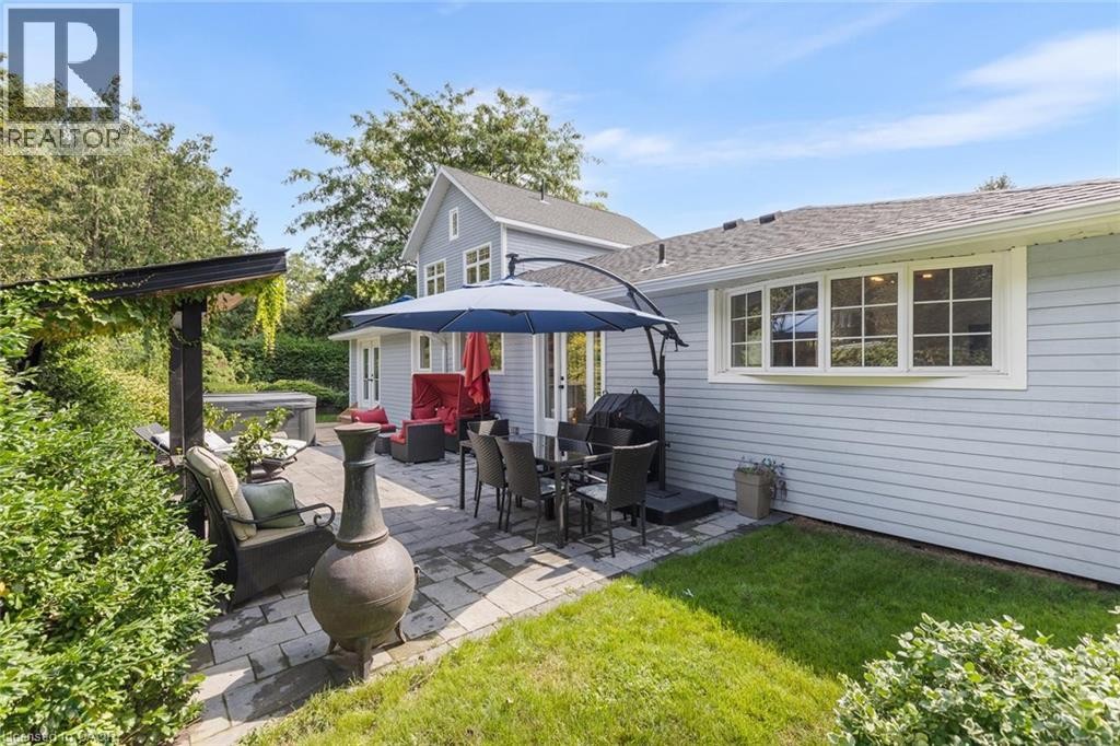 Expansive paver patio with a pergola, built-in hot tub, and lush surrounding landscaping - 293 North Shore Boulevard E, Burlington, ON