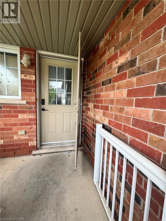Brick exterior with contrasting trim, covered entry, and a white aluminum railing - 717 Activa Avenue, Kitchener, ON