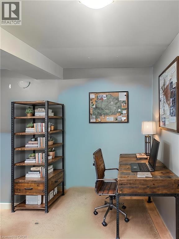 Dedicated home office featuring a light blue accent wall, wood-finish desk with rolling chair, industrial-style shelving unit with mixed storage and display space, framed artwork, and recessed ceiling - 717 Activa Avenue, Kitchener, ON