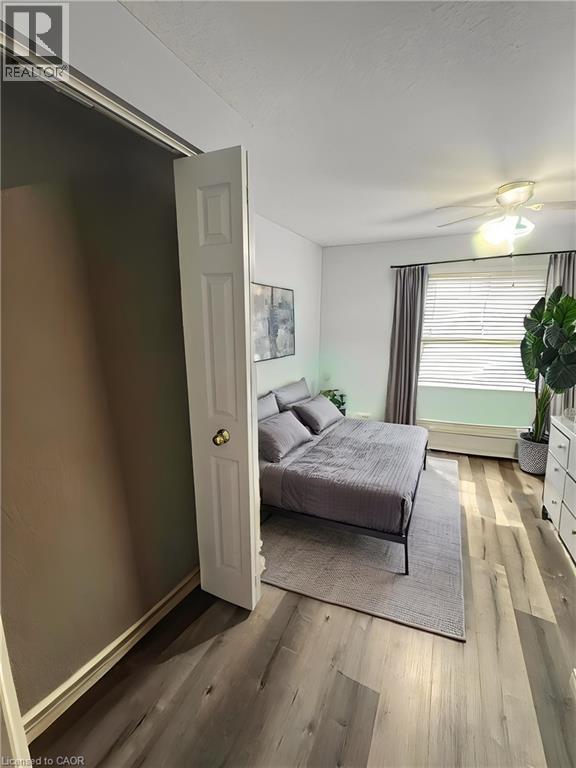 Wood-finish flooring, ceiling fan with integrated lighting, window with blinds and drapes, and a baseboard heater - 717 Activa Avenue, Kitchener, ON