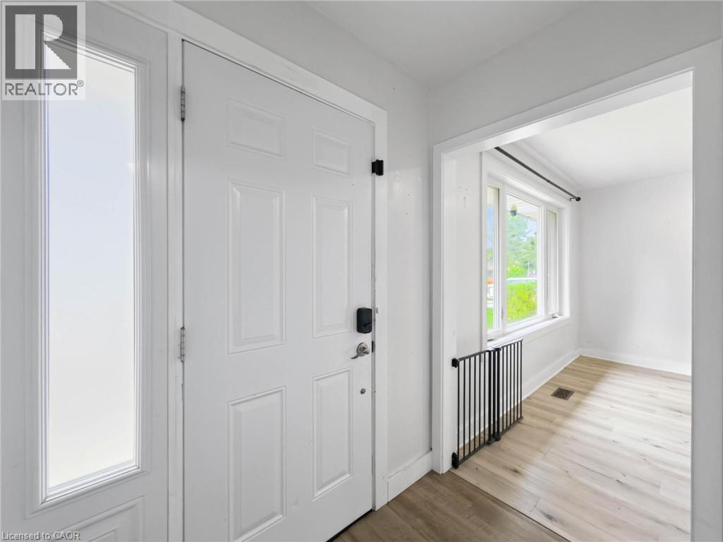 Entry door with frosted glass sidelight, light wood-finish flooring, and bright white walls - 220 Cairn Street, London, ON