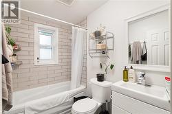 White subway tile surround, white bathtub, single vanity with integrated sink, framed wall mirror, and white panel door - 
