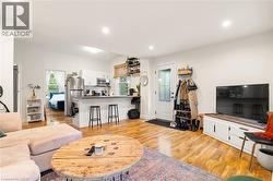 Hardwood flooring throughout, recessed lighting, and a kitchen featuring a breakfast bar with white cabinetry, stainless steel appliances, and a window - 