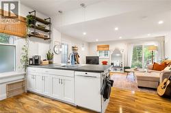 Open-concept living area featuring wood-finish flooring, white cabinetry, a built-in dishwasher, recessed lighting, and a sliding glass door to the exterior - 