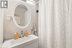 White oval framed mirror, integrated sink vanity, chrome faucet, and tiled shower surround - 