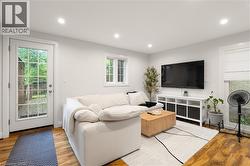Recessed lighting illuminates this bright room featuring wood-finish flooring, a white window, and a glass-paneled door - 