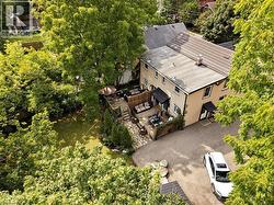 Expansive paved driveway leading to a multi-level outdoor patio with natural stone accents and a dedicated outdoor dining area - 