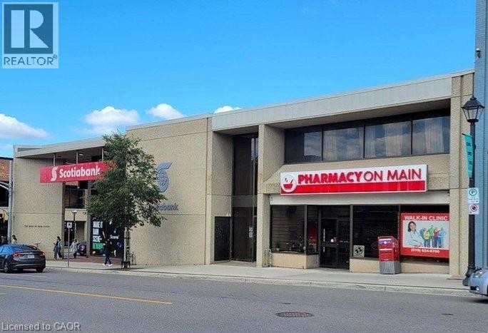 Commercial building with a stone-finish facade, multiple storefronts, and integrated signage - 72 Main Street, Cambridge, ON