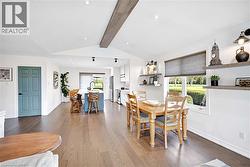 Expansive open-concept living area featuring wood flooring, recessed lighting, and a vaulted ceiling with a decorative beam - 