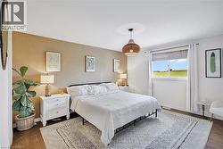 Bright bedroom featuring a textured accent wall, wood flooring, and a large window with a distant landscape - 