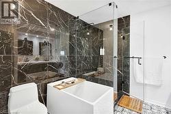 Bathroom featuring dark veined wall tile, glass-enclosed shower, white freestanding soaking tub, and patterned floor tile - 