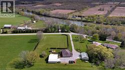 Aerial view showcasing the property's expansive grounds, a paved driveway, and surrounding green fields - 
