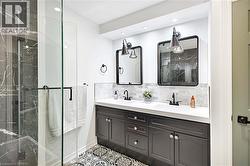 Bathroom featuring a dual vanity with dark cabinetry, white countertops, and black fixtures - 