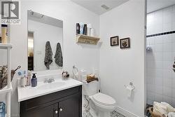 Bathroom featuring a dark vanity with a white countertop, an integrated sink, and a rectangular wall mirror - 