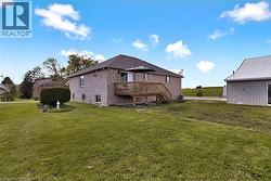Brick exterior residence featuring a wood deck with stairs, a spacious lawn - 