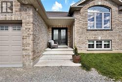 Brick exterior featuring a gabled roofline, arched window with divided lites, double entry doors, a concrete entryway, and an attached garage with panel detailing - 